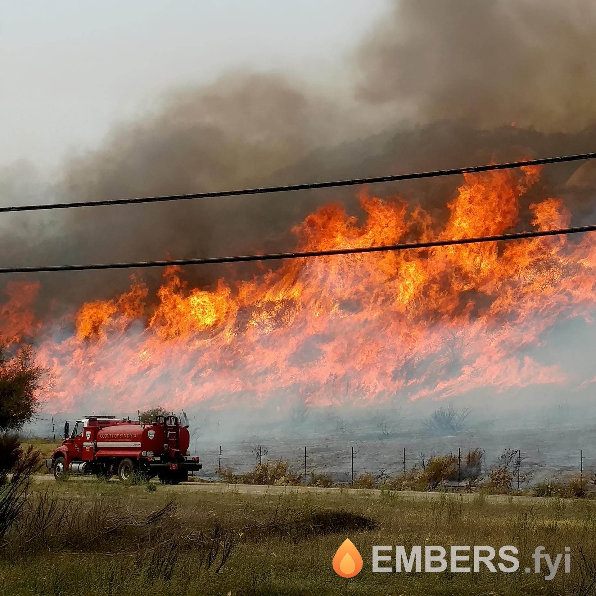 Wildfire with large flames and fire truck responding near the border in San Diego