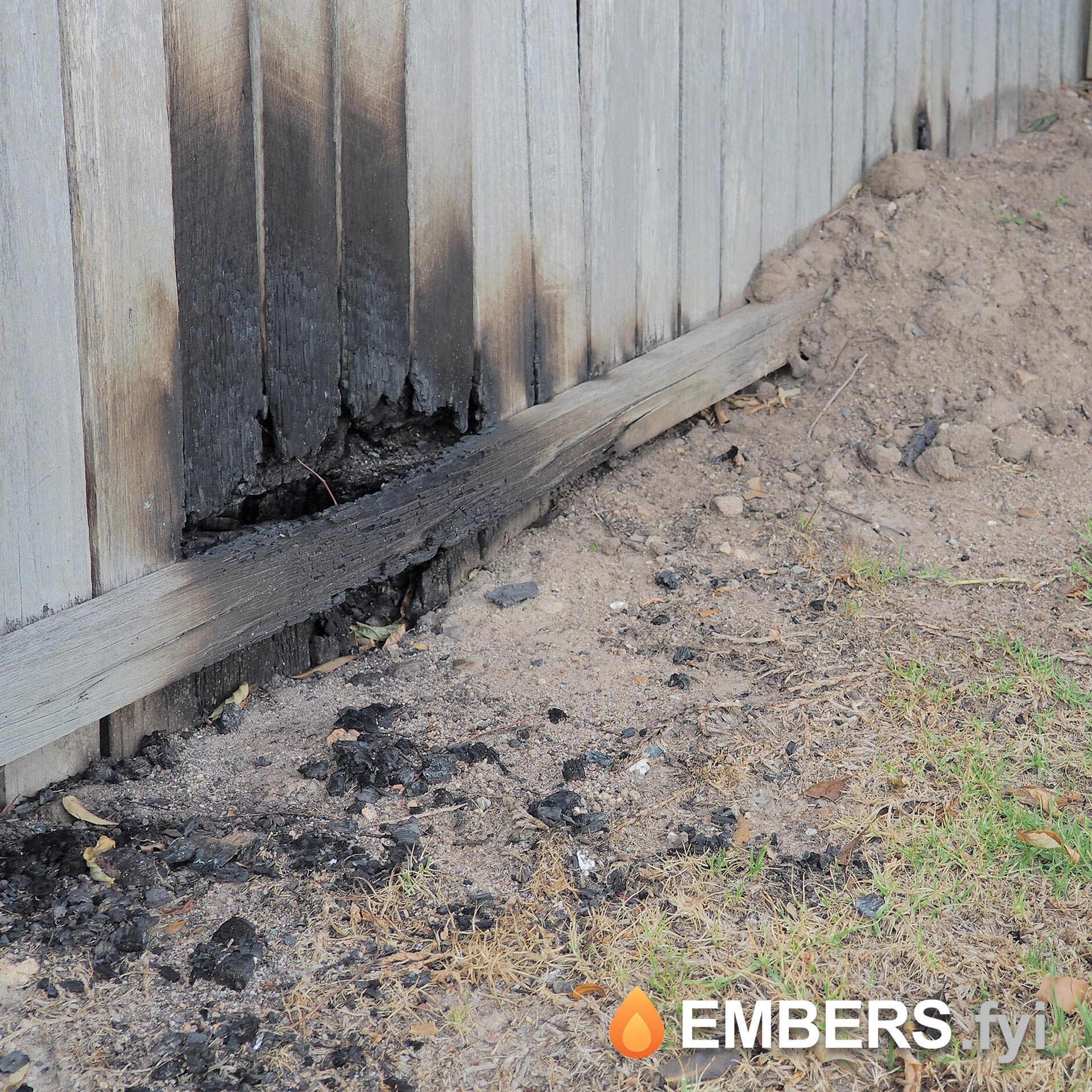 Wooden fence severely charred and damaged by embers